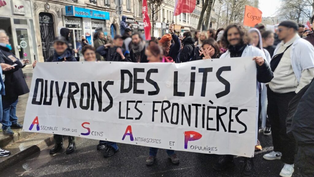 Des gens manifestent avec une banderole : "Ouvrons des lits et des frontières"